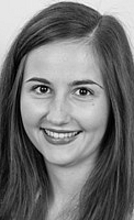 Julia Faller Eine junge Frau mit langen, braunen Haaren lächelt in die Kamera. Sie trägt ein leicht glitzerndes Oberteil und hat einen warmen, freundlichen Ausdruck. Der Hintergrund ist einfarbig und neutral.